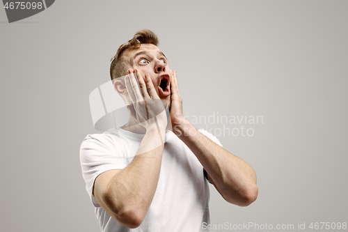 Image of The young attractive man looking suprised isolated on gray