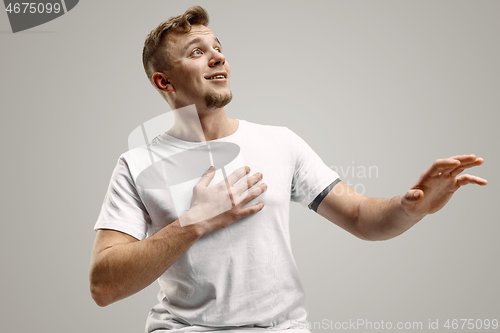Image of The young attractive man looking suprised isolated on gray