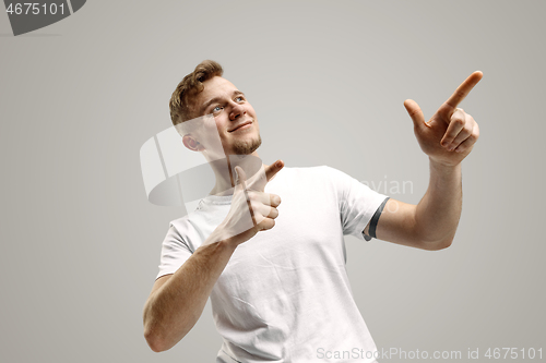 Image of Stylish handsome young man pointing at studio