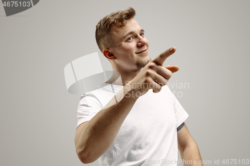 Image of Stylish handsome young man pointing at studio