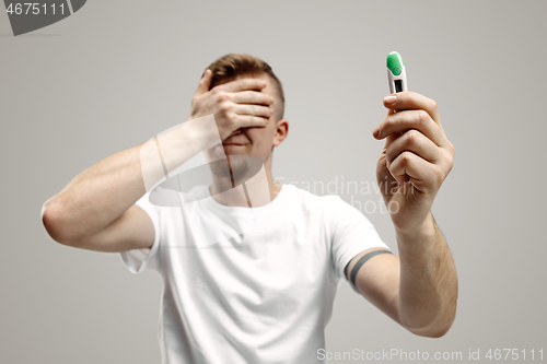 Image of Upset man looking in pregnancy test. Frustrated model