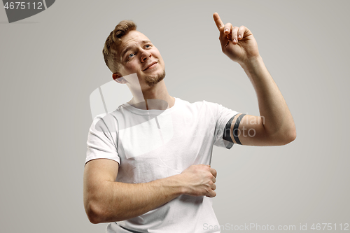 Image of Stylish handsome young man pointing at studio