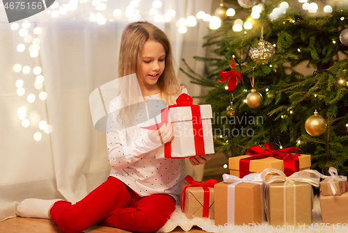 Image of smiling girl with christmas gift at home