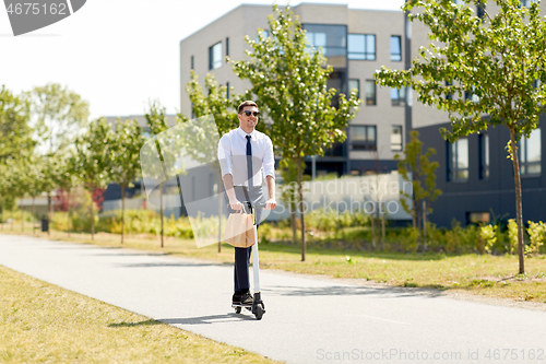 Image of businessman with lunch in paper bag riding scooter