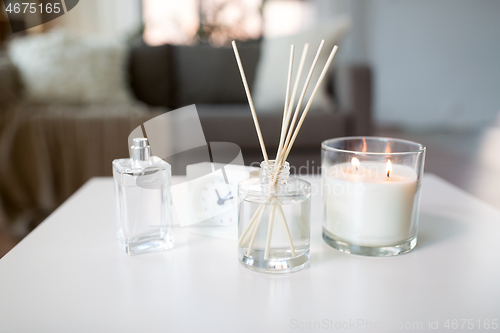 Image of aroma reed diffuser, burning candle and perfume