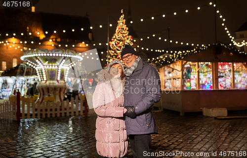 Image of happy senior couple hugging at christmas market