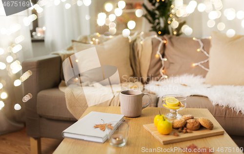 Image of tea with lemon, book and cookies on table at home