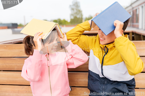 Image of school children with books having fun outdoors