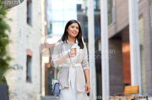 Image of smiling woman with takeaway coffee cup in city