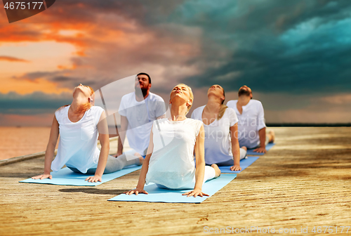 Image of group of people making yoga exercises outdoors