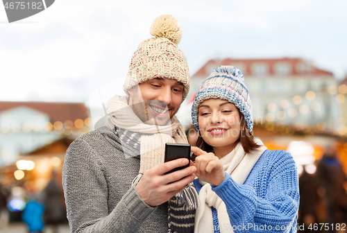 Image of happy couple with smartphone christmas market