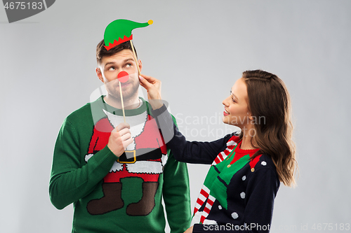 Image of couple with christmas party props in ugly sweaters