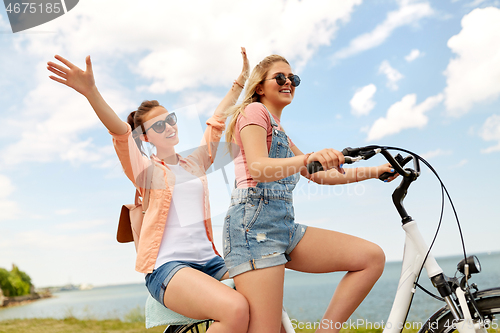 Image of teenage girls or friends riding bicycle in summer