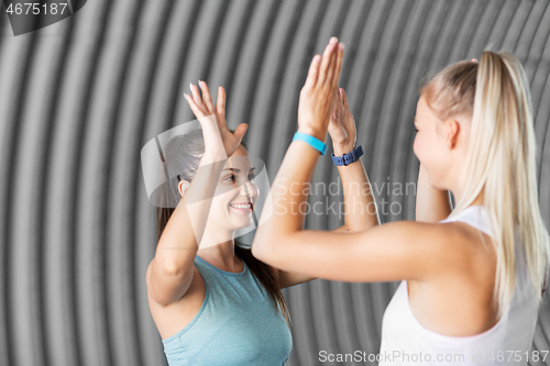 Image of happy women with fitness trackers making high five