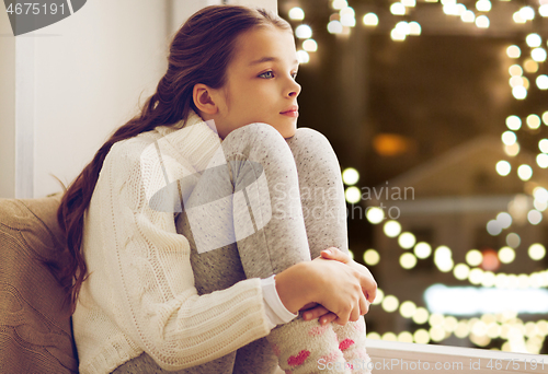 Image of sad girl sitting at home window on christmas