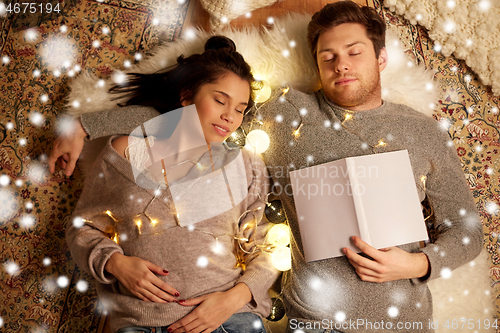 Image of happy couple with garland lying on floor at home