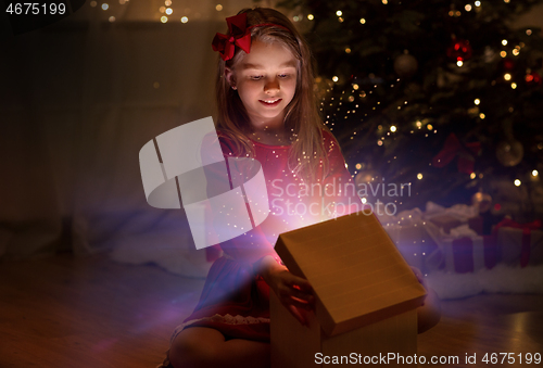 Image of smiling girl opening christmas gift at night