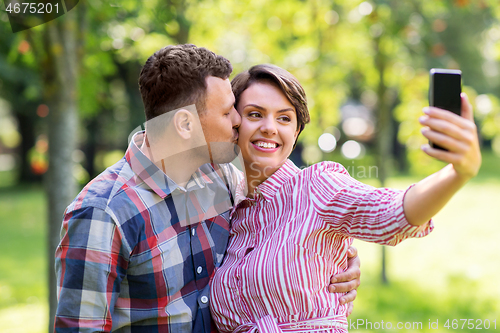 Image of happy couple in park taking selfie by smartphone