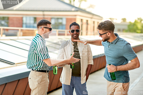 Image of happy male friends drinking beer at rooftop party