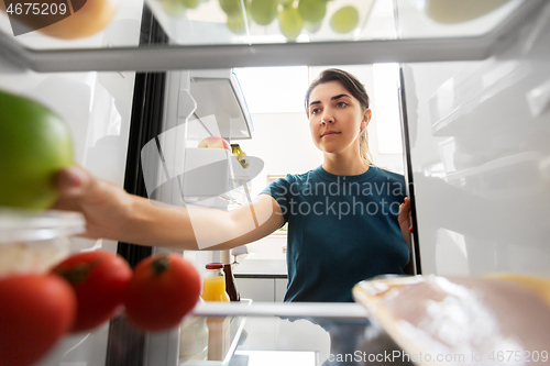 Image of woman taking food from fridge at home