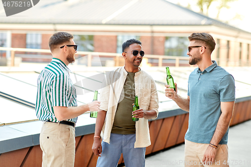 Image of happy male friends drinking beer at rooftop party