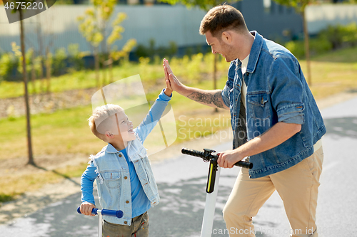 Image of father and son with scooters making high five