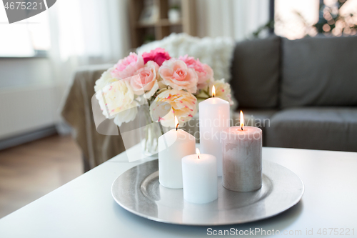 Image of candles burning on table and flowers at cozy home