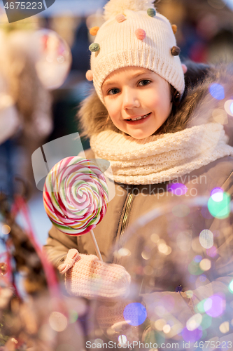 Image of litle girl with big lollipop at christmas market