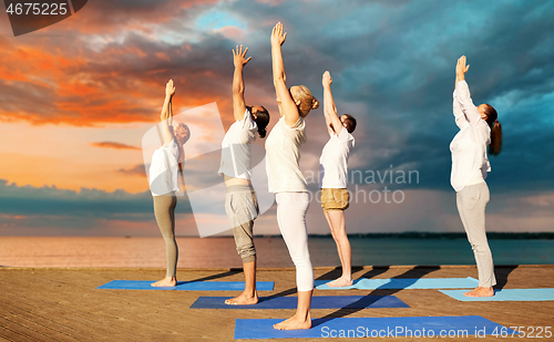 Image of group of people making yoga exercises outdoors