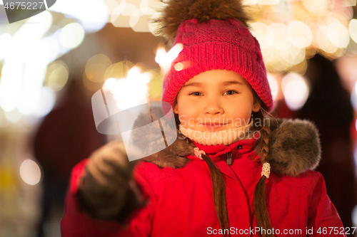 Image of happy girl with sparkler at christmas market