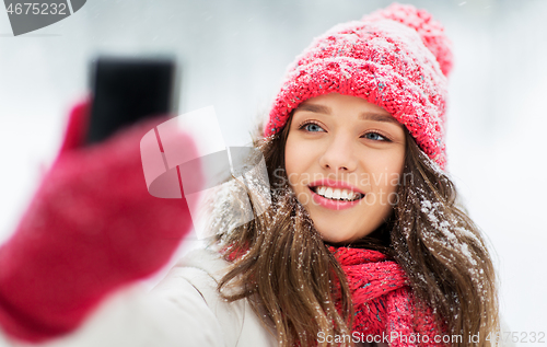 Image of young woman taking selfie by smartphone in winter