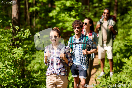 Image of group of friends with backpacks hiking in forest