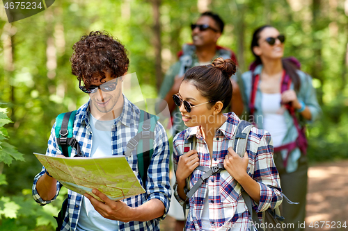 Image of friends with map and backpacks hiking in forest