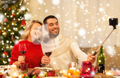 Image of couple taking picture by selfie stick at christmas