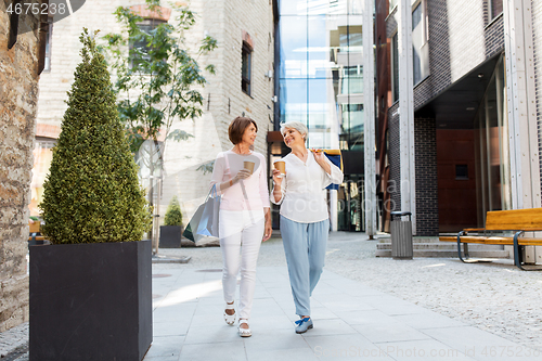 Image of senior women with shopping bags and coffee in city