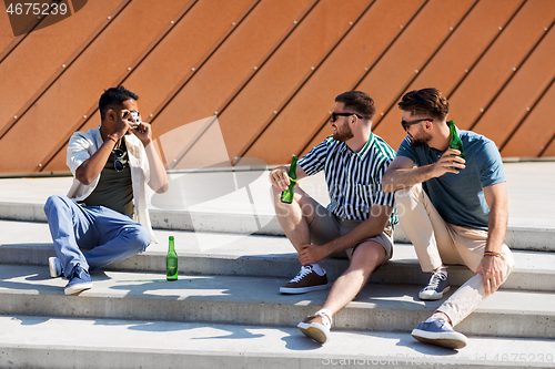 Image of man photographing friends drinking beer on street