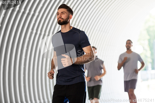 Image of young men or male friends running outdoors