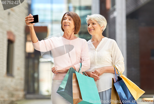 Image of old women with shopping bags taking selfie in city