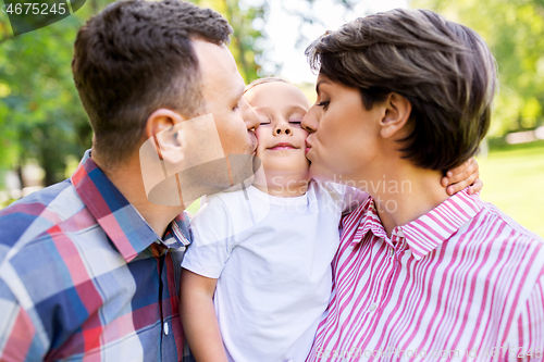 Image of mother and father kissing their little son at park