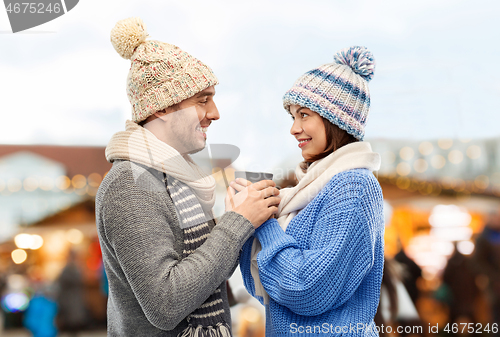 Image of happy couple holding one cup at christmas market