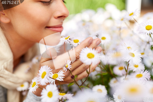 Image of close up of happy woman smelling chamomile flowers