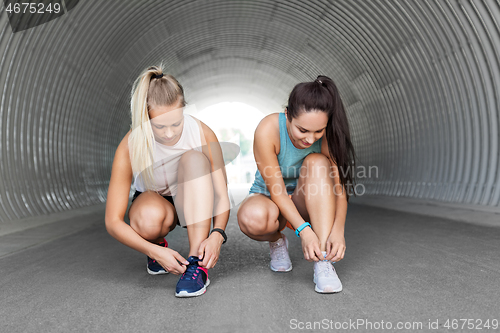 Image of sporty women or female friends tying shoe laces