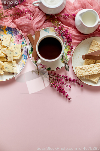 Image of Hot chocolate or cocoa in cup with various sweets on sides. White chocolate bar and biscuits