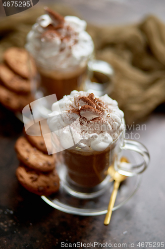 Image of Two tall glasses with hot chocolate, whipped cream and cinnamon powder on top