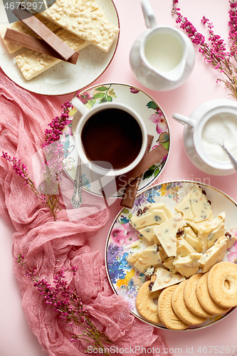 Image of Hot chocolate or cocoa in cup with various sweets on sides. White chocolate bar and biscuits