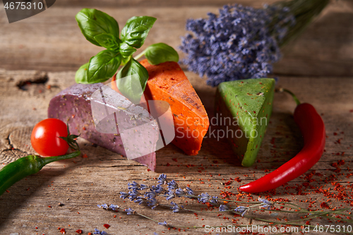 Image of Three different cheeses on rough wooden planks: lavender, paprika and pesto cheeses