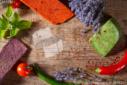 Image of Three different cheeses on rough wooden planks: lavender, paprika and pesto cheeses