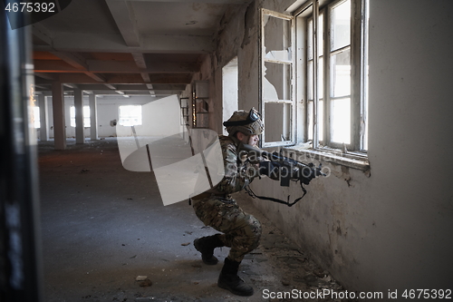 Image of soldier in action near window changing magazine and take cover