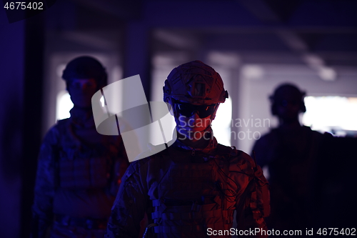 Image of soldier squad team walking in urban environment colored lightis