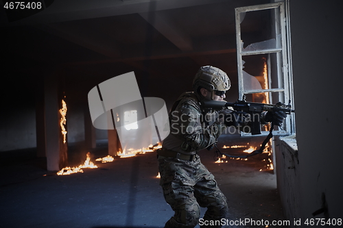 Image of soldier in action near window changing magazine and take cover